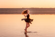 © farmuty - Bright, sunny Silhouette of young curly dancer in airy black dress in the water of lake with sky