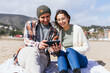 © ADDICTIVE STOCK - Content couple browsing smartphone on beach