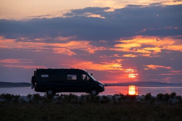 Poster - Backlighting silhouette of a camper next to a salt lake at sunset with the sun reflecting in it