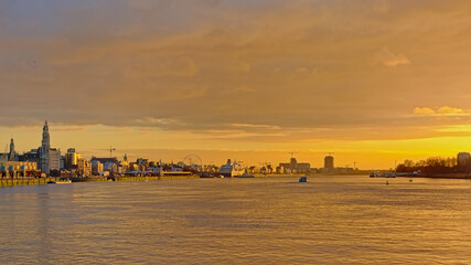 Antwerp skyline with ferris wheel, skyscrapers and cruise ship, view from across river Scheldt in warm orange light after sunset 