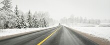 Empty Highway (asphalt Road) Through The Snow-covered Forest And Field. USA. Nature, Christmas Vacations, Remote Places, Winter Tires, Dangerous Driving Concept