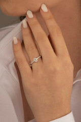 Beautiful lady's hand. woman wearing a white blouse and a diamond ring on her finger.