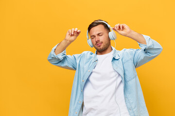 Joyful relaxing tanned handsome man in blue basic t-shirt headphones move on cool song closing eyes posing isolated on orange yellow studio background. Copy space Banner Mockup. Time to relax concept