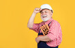 smiling senior man bricklayer in hard hat on yellow background