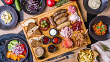 Assorted Sausages With Sauces, Sliced Different Meat, Pastrami, Parma Ham, Rack Of Lamb, Mashed Celery, French Fries, Mashed Potatoes, Vegetable Salad And Beetroot Salad With Cheese Top View Food