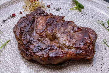 Sticker - juicy Ribeye steak on grey plate on dark stone table macro close up