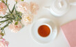 Close up of soft pink carnations from above with tea cup, journal and tea pot in background (selective focus)