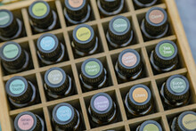 Top-down View Of Essential Oil Bottles In Wooden Storage Box With Colorful Cap Stickers