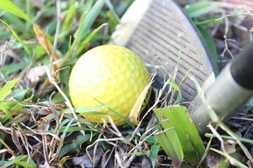 Close up of a yellow golf ball in front of the club head of a 9 iron