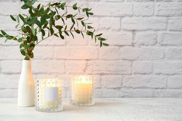 Wall Mural - Glass holders with burning candles and eucalyptus branches on light table