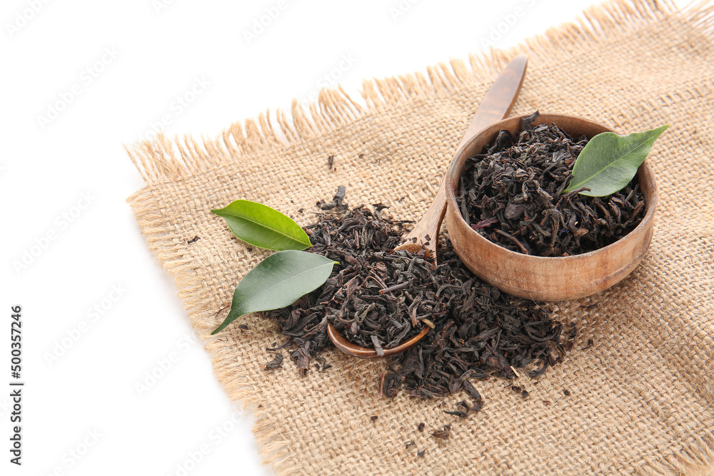 Bowl and spoon with dry tea leaves isolated on white