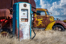 Antique Gas Pump In The Foreground And Vintage Truck In The Background