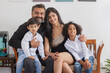 © IndiaPix - Portrait of happy couple sitting on sofa with their children in living room