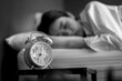 © thebigland45 - Young woman turning off alarm clock in morning late without looking clock. Relaxation and people lifestyles of tired worker.