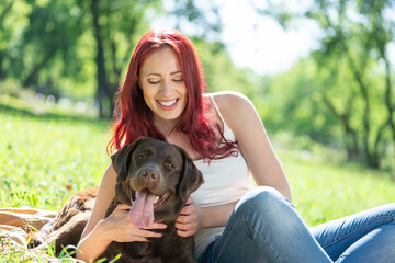 Poster - Young attractive woman hugs her dog in the park.