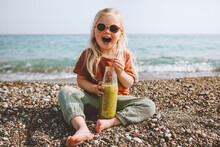 Child Drinking Smoothie On Beach Healthy Lifestyle Summer Vacations Child With Reusable Glass Bottle Vegan Organic Beverage Picnic Outdoor Kid Laughing Happy Emotions