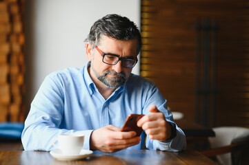 man in casual form using mobile phone at the cafe