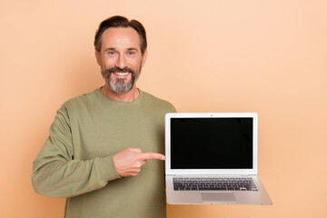portrait of attractive trendy cheerful man demonstrating laptop copy space ad isolated over beige pa