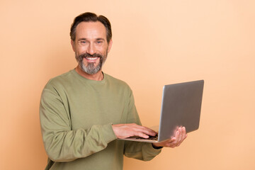 Sticker - Portrait of attractive cheerful successful skilled man using laptop web surfing isolated over beige pastel color background