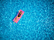 © artiemedvedev - Fit pretty girl in bikini chilling on inflatable pink mattress in swimming pool. Slim hot woman in swimwear tanning. Female relaxing on float in blue water at luxury resort. Aerial, view from above.