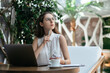 © yurolaitsalbert - thoughtful business woman sitting in front of an open laptop in a cafe.