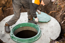 A Utility Worker Opened A Well Hatch For Sewerage Maintenance And Pumping Out Feces. Septic On A Residential Lot