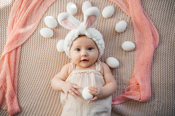 newborn baby lies on a bed in pastel colors like an easter bunny on the grass with eggs