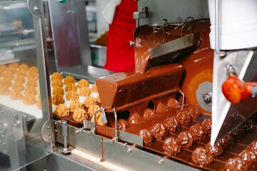 sweets production and industry concept - chocolate candies processing on conveyor at confectionery shop.