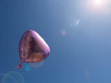 Fototapeta  - Inflatable pink heart-shaped balloon against the sky and sunbeams.copy space