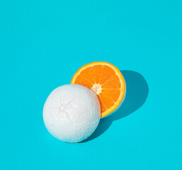 Wall Mural - White painted orange fruit cut in half on pastel blue background. Minimal summer concept. Flat lay.