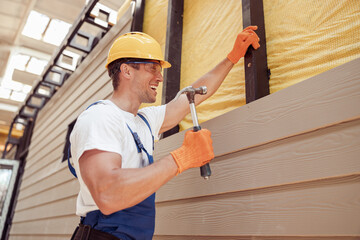 Wall Mural - Joyful male builder using hammer at construction site