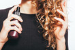 Close-up young woman spraying cosmetic oil to tips