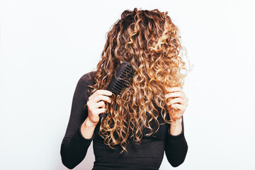 Wall Mural - Unrecognizable young woman combing her naturally curly hair