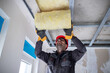 Male worker insulating attic with glass wool.