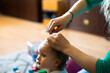 mother corrects baby girl hair at natural home blurred background