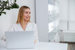 © Friends Stock - Joyful female cosmetologist using laptop in beauty salon