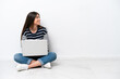© luismolinero - Young caucasian woman with a laptop sitting on the floor isolated on white background in lateral position