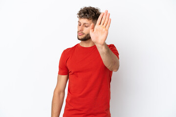 Young caucasian handsome man isolated on white background making stop gesture and disappointed