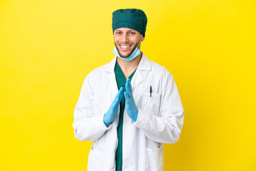 Wall Mural - Surgeon blonde man in green uniform isolated on yellow background applauding after presentation in a conference