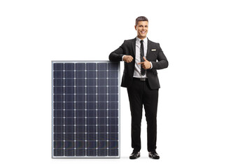 Wall Mural - Full length portrait of a professional man in suit and tie leaning on a solar panel and pointing