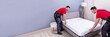 © Andrey Popov - Young Male Movers Placing The Mattress Over The Bed