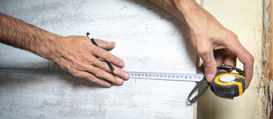 Wall Mural - Carpenter marking laminate with tape measure and pencil.