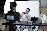 Fototapeta Łazienka - Young attractive Asian man blogger or vlogger looking at camera reviewing product. Modern businessman using social media for marketing. Business online influencer on social media concept.