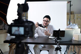 Fototapeta Łazienka - Young attractive Asian man blogger or vlogger looking at camera reviewing product. Modern businessman using social media for marketing. Business online influencer on social media concept.