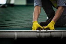 A Man Worker Is Cleaning A Clogged Roof Gutter From Dirt, Debris And Fallen Leaves To Prevent Water And Let Rainwater Drain Properly.