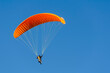 Paragliding orange flying against blue sky. Adventure sport.
