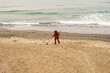 Man with a metal detector walks along the beach in a red suit. Slow motion, 4k, slow motion