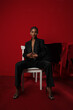 © face_reader_img - Vertical portrait of African young woman with braids wears dark suite on red.