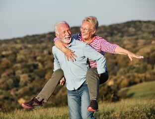 Wall Mural - woman man outdoor senior couple happy lifestyle retirement together smiling love piggyback active ma