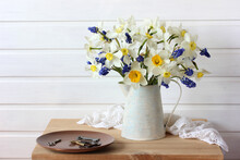 White Daffodils With A Yellow Center And Blue Muscari In A Jug